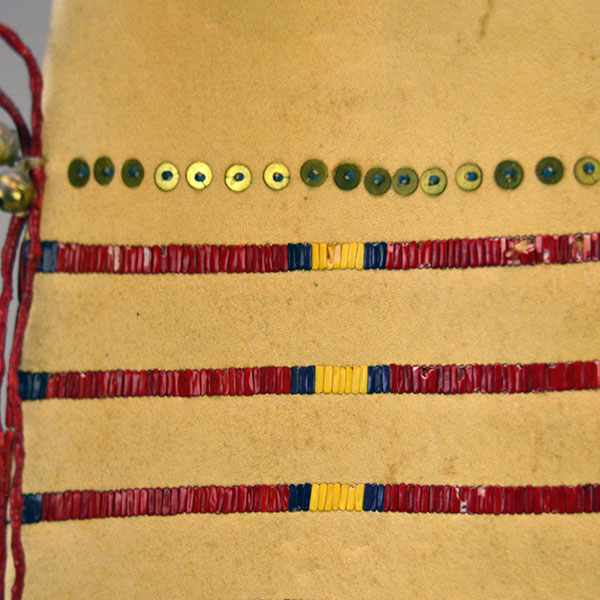 Pipe Bag- Double-sided Quillwork, Braintanned deerskin, braided fringe, cone‑drop tassels, and brass bells. Measures 45" with light age wear. The back showing the quillwork and the brass sequences.