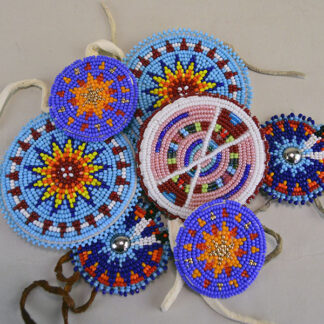 Seven‑piece Rosette Group Lot featuring matching sets, a pin rosette, Braintanned lacing, and dimensional edging. The lot offers mix of sizes. one of a kind.