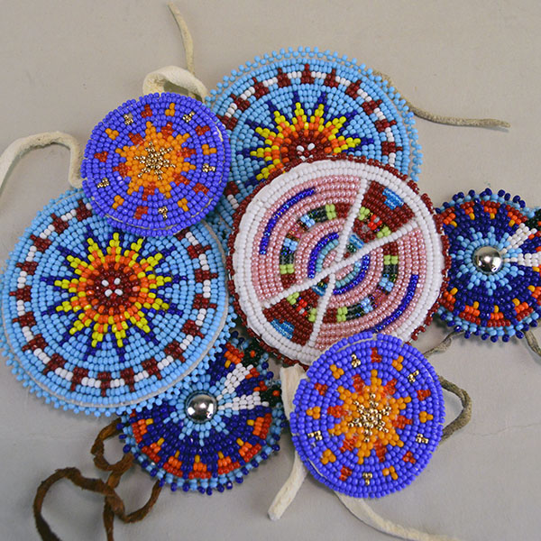 Seven‑piece Rosette Group Lot featuring matching sets, a pin rosette, Braintanned lacing, and dimensional edging. The lot offers mix of sizes. one of a kind.