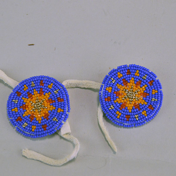 Seven‑piece Rosette Group Lot featuring matching sets, a pin rosette, Braintanned lacing, and dimensional edging. The lot offers mix of sizes. one of a kind. The front of the periwinkle color rosette.