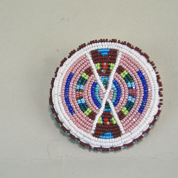 Seven‑piece Rosette Group Lot featuring matching sets, a pin rosette, Braintanned lacing, and dimensional edging. The lot offers mix of sizes. one of a kind. The front of the pin rosette.