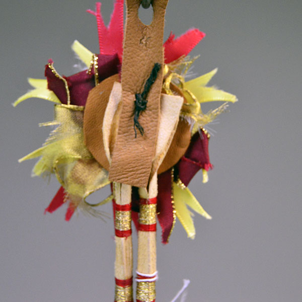 Scalp Feather- Gold Rosette, Hand‑painted eagle feathers, ribbon accents, and cowrie shell tassels. measures approx. 16.5" long. pictured here is the back showing how the crafter attached the rosette to the feathers.