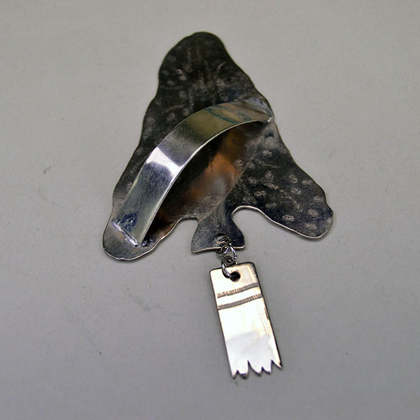 German silver Scarf Slide- Arrowhead with stamped designs and rectangular drop. Handmade piece in very good condition, measuring 4″ by 2.25″. Pictured here is the back showing the attached metal loop and the back of the drop.