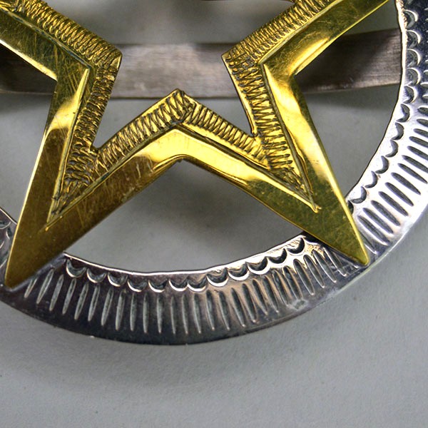 Hand‑stamped Brass Star Scarf Slide with German silver circle base. Measures 2.5″ x 2.5″. Bold, compact accessory for regalia, bandanas, and neckerchiefs. The stamped brass star and the German silver circle.