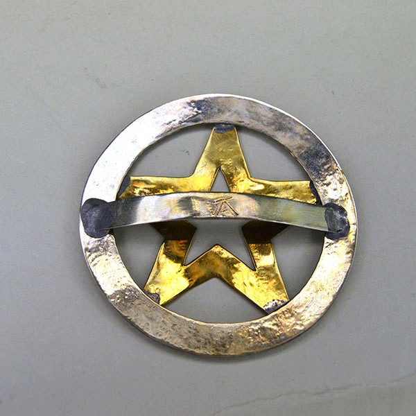 Hand‑stamped Brass Star Scarf Slide with German silver circle base. Measures 2.5″ x 2.5″. Bold, compact accessory for regalia, bandanas, and neckerchiefs. Pictured is the back showing the rounded metal loop on the back.