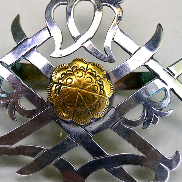 Scarf Slide- Double Strawberry with hand stapled brass concho, maker’s mark, and smooth soldered loop. Compact 2.5″ x 2.75″. Here is a close up of the stamped center brass concho.