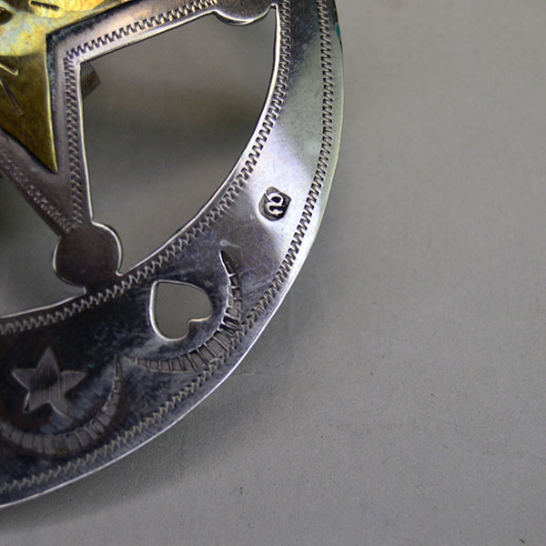 Handmade German silver Scarf Slide- Hearts & Stars, a brass accent, and a maker’s mark. Measures 3″ for bold regalia or everyday neckwear. pictured here is the makers mark.