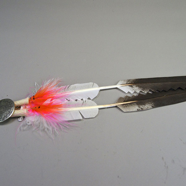Scalp Feather- Stamped Concho, Hand‑painted scalp feather with a stamped concho, cut designs, pink fluffs, and traditional detailing. Measures 12.5 inches. Pictured here is the hand painted feather, the cut design, the orange and pink fluffs with the hand stamped concho.