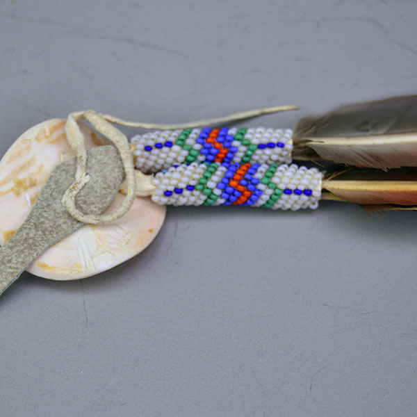This striking Blue Macaw Scalp Feather & Conch blends bold natural feathers with detailed beadwork and traditional beadwork. Pictured here is the back of the pink concho and how it was held on.