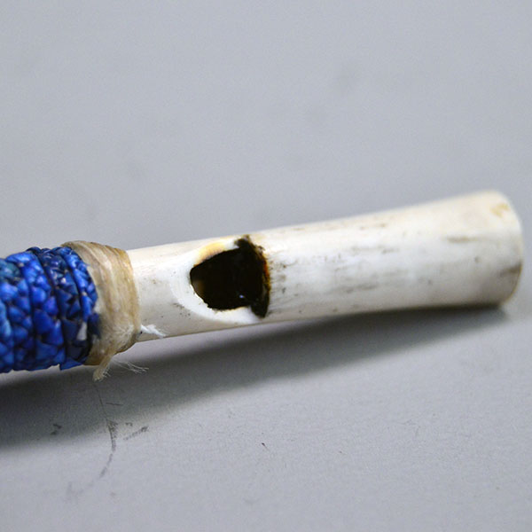 Whistle- Bird Wing Bone Quilled with braided red, white, and blue porcupine‑quillwork and a secure sinew wrap. Approx. 5.5 inches long. One of a kind. The opening for the sound to go through.