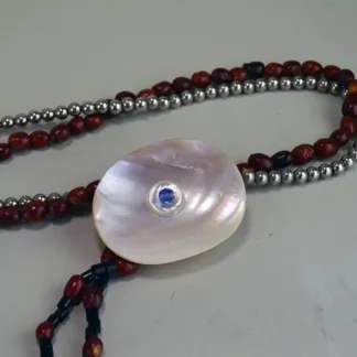 Bandolier- Nickel & Mescal Beads with a pink shell centerpiece, blue fire‑polished bead, and a 5‑inch drop. and in good usable condition. Approx. 36" long .