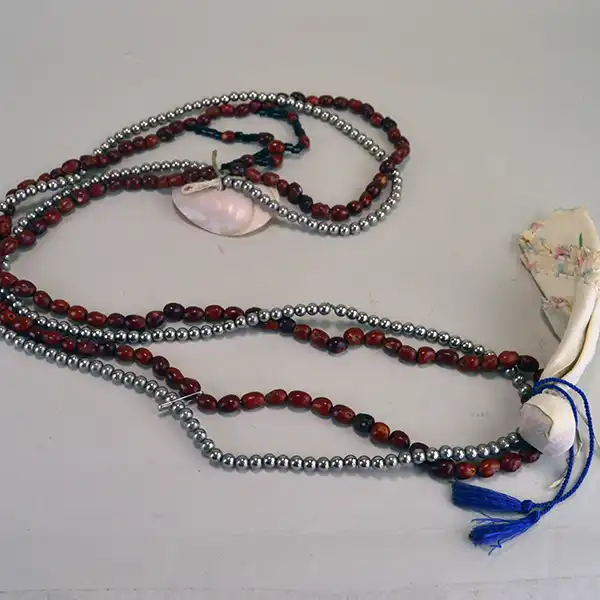 Bandolier- Nickel & Mescal Beads with a pink shell centerpiece, blue fire‑polished bead, and a 5‑inch drop. and in good usable condition. Approx. 36" long . Showing the back side.