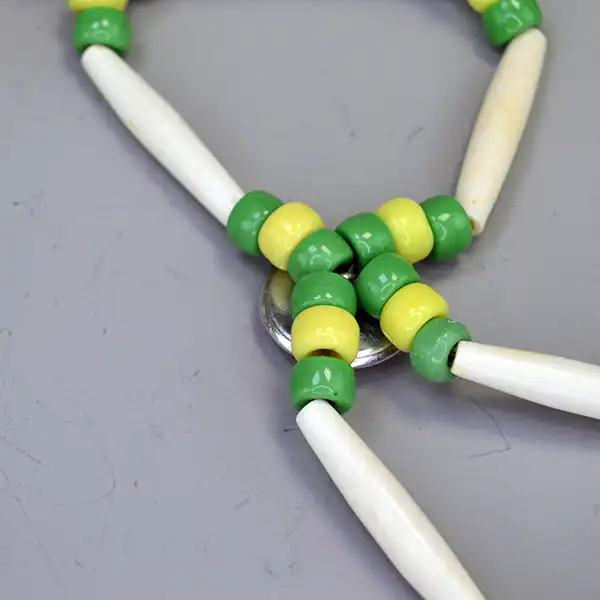 Handcrafted bone hairpipe Choker- Green & Yellow Crow beads, white-center pony beads, deerskin leather. approx. 15 inches. One of a Kind. The back of the drop .