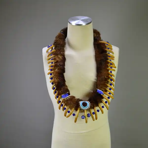 Necklace- Carved Bear Claw with cobalt blue glass beads and a removable ribbon work drop featuring beadwork, silver brooches, and otter fur. One of a Kind.