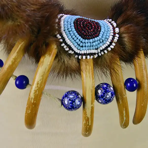 Necklace- Carved Bear Claw with cobalt blue glass beads and a removable ribbon work drop featuring beadwork, silver brooches, and otter fur. One of a Kind. The beaded design with the bear claws' and the beads.