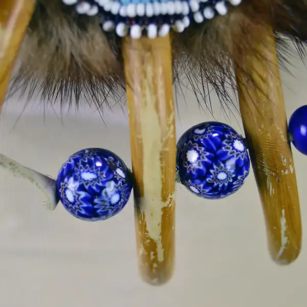 Necklace- Carved Bear Claw with cobalt blue glass beads and a removable ribbon work drop featuring beadwork, silver brooches, and otter fur. One of a Kind. The blue and white trade beads on the front.