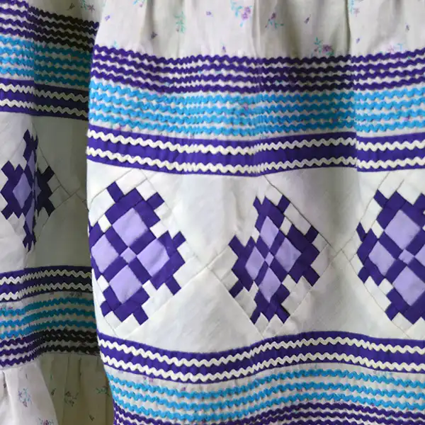 Vintage Skirt- Floral White Seminole with purple patchwork, turquoise rickrack, stretched elastic waist. Estimated to be a girls size XL or a women's XS. the purple patch work design.