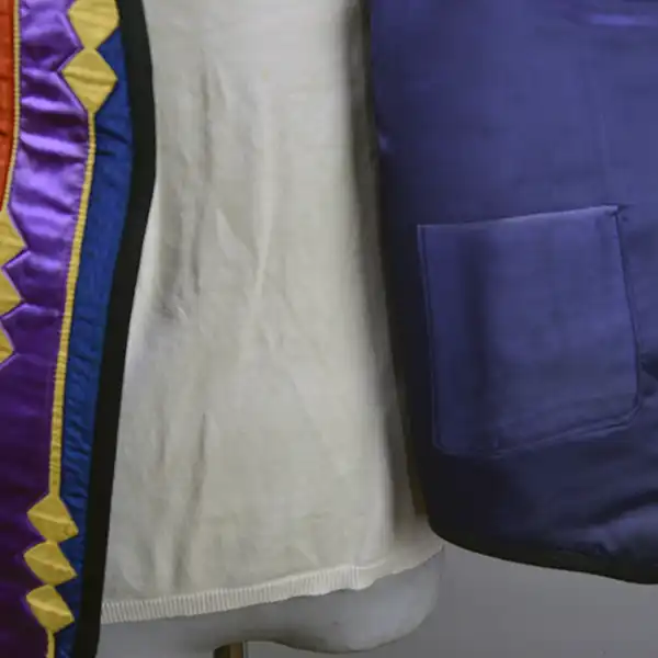Contemporary Vest- Ribbon Work featuring vibrant purple, orange, gold, and blue designs, black fox braid trim, silk lining, and a red corduroy back. The inside blue silk lining and the pocket